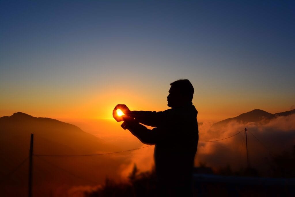 A captivating silhouette of a man capturing the sunrise over foggy mountains.