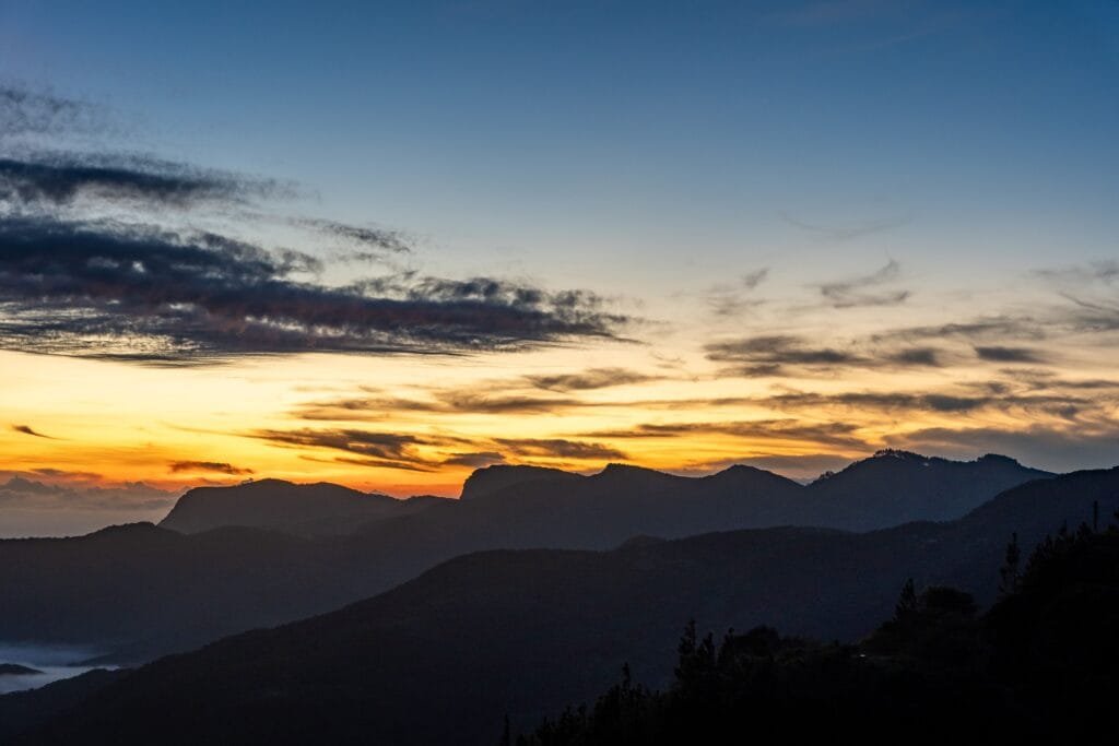 Serene sunrise over the misty mountain range in Sri Lanka, featuring a vibrant sky.