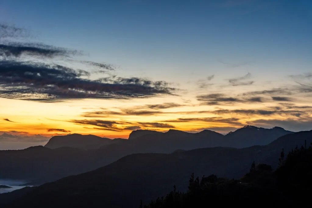 Serene sunrise over the misty mountain range in Sri Lanka, featuring a vibrant sky.